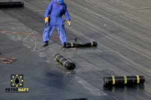 Worker applying bituminous membrane on roof with torch