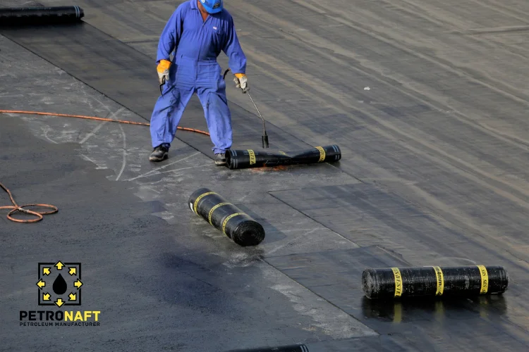 Worker applying bituminous membrane on roof with torch