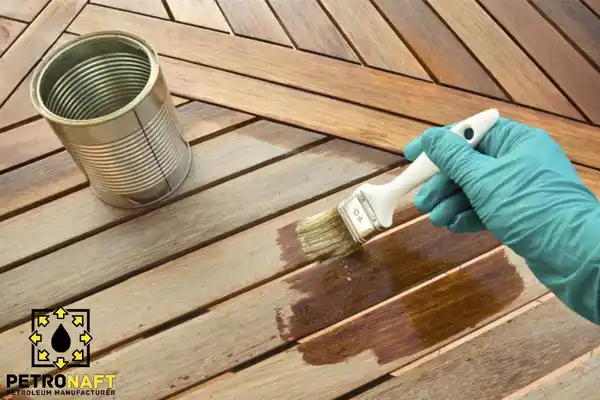A person staining wood with a brush, stain made with gilsonite
